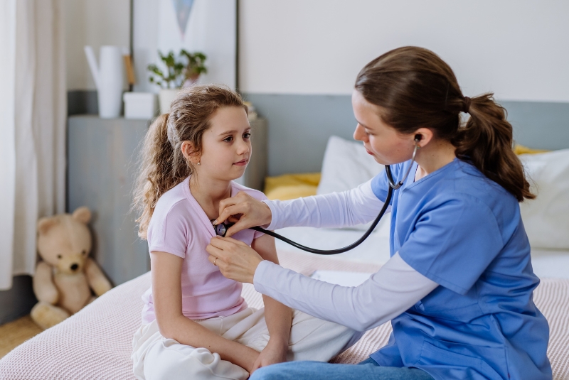 A young girl has her lungs checked by a doctor