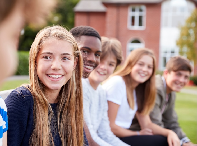 Adolescents sitting in a line smiling