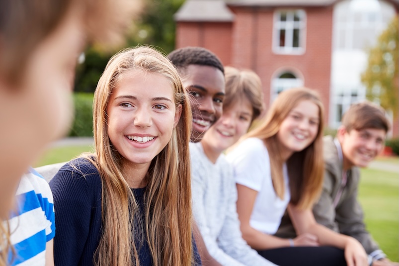 Adolescents sitting in a line smiling