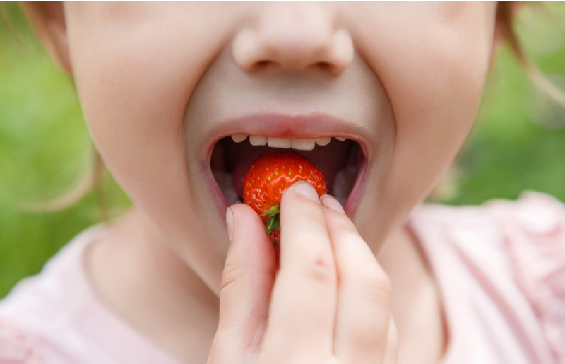 child eating strawberries