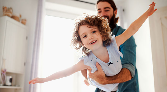 Girl flying in parent's arms